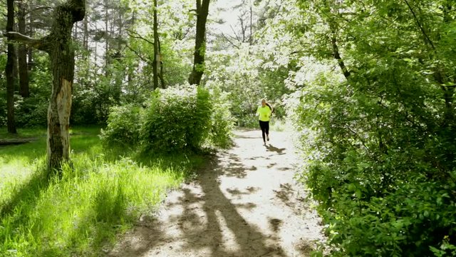 Sport girl running on forest path in park. Sunny day. Stop then have rest full HD