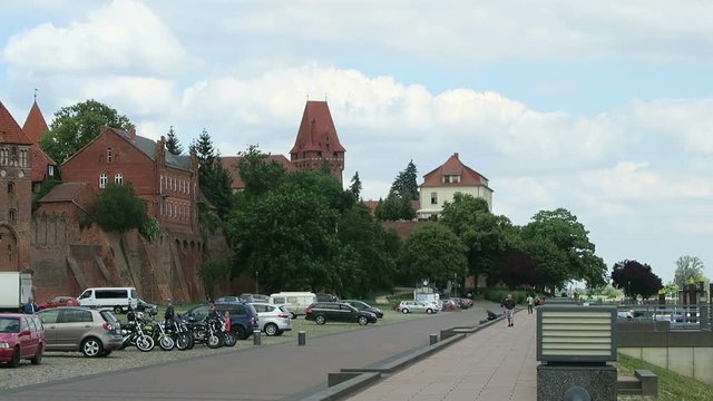 TANGERMUENDE, SAXONY-ANHALT/ GERMANY June 29 2016: historical brick stone town wall of Tangermuende directly on Elbe river. People walking along and cars parking.
