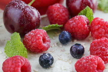 Raspberry, sweet cherry and bilberry on white wooden background.