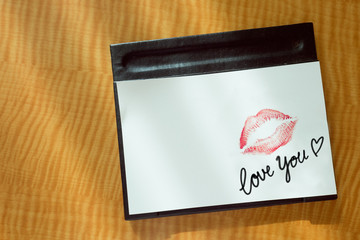 Sexy girl Red lips kiss and "Love you" word write on white note paper on bed stand table in the morning light. 
romantic message from couple.