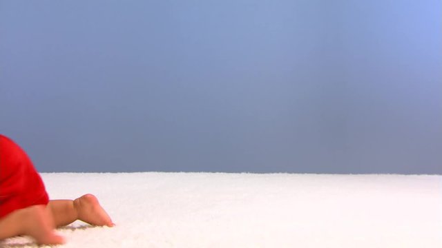 Baby in red playsuit crawling through frame from right