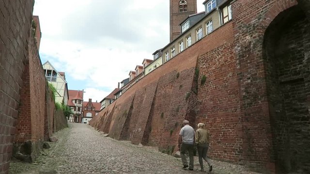 TANGERMUENDE, SAXONY-ANHALT/ GERMANY June 29 2016: Couple walking along the street at town wall of Tangermuende toward the center with its half-timbered houses.