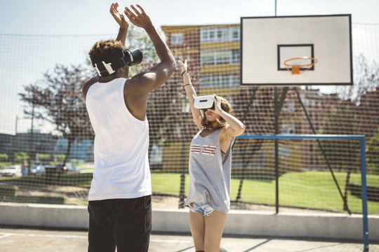 Young couple playing basketball with virtual reality glasses on