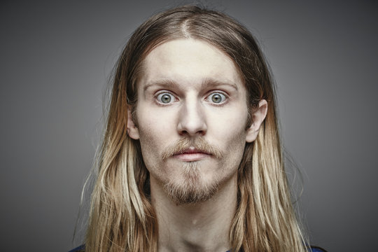 Portrait of starring young man with long blond hair and beard