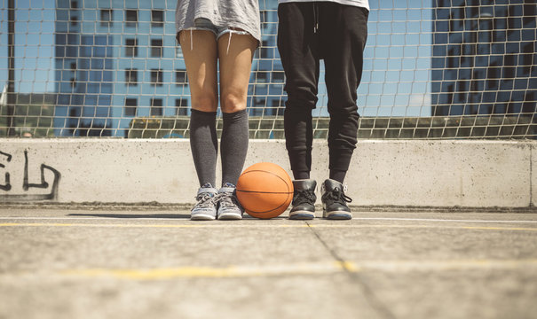Young man and woman standing on basketball field with between their feet