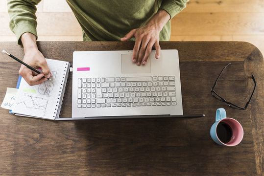 Man at wooden desk with laptop taking notes