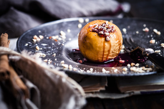 Baked apple with nut- and red jam filling on tin plate