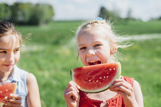 Two girls outdoors eating slices of watermelon