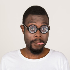 junger Mann mit dunkler Hautfarbe hat Spaß und zieht Grimasse mit Brille