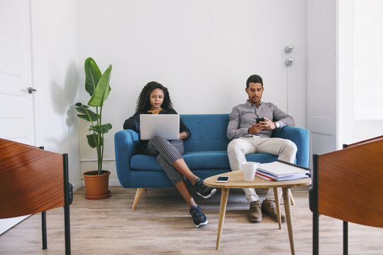 Young business people working relaxed on couch