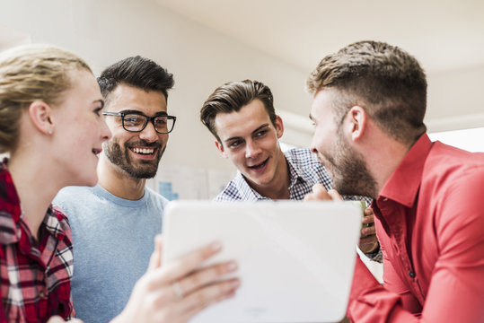 Smiling young professionals with digital tablet in office