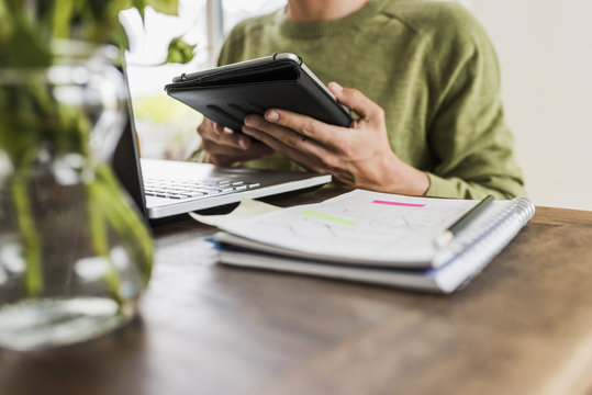 Man at wooden desk with laptop and digital tablet