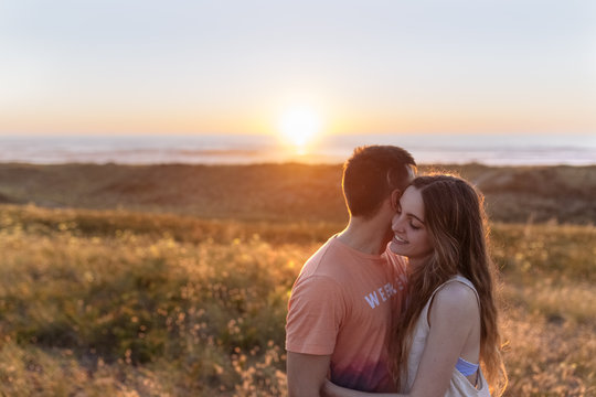Romantic young couple embracing on the beach at sunset