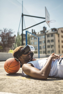 Young couple using virtual reality glasses, resting heads on basketball