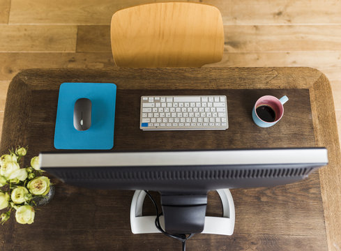 Wooden desk with keyboard, coffee cup and mouse