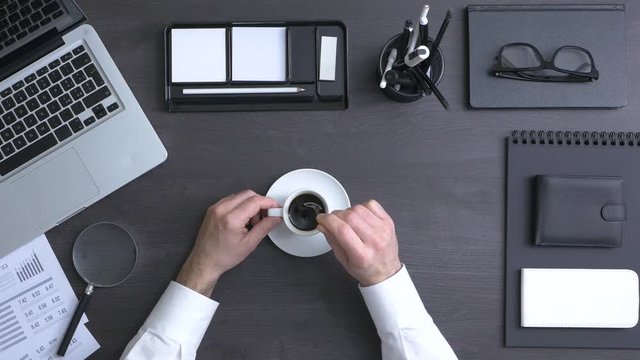 Businessman working at office desk and having a coffee break, top view