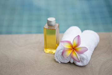 Spa concept, white towel with shamphoo bottle and flower at swimming pool