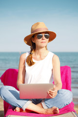 Woman working on laptop on the beach