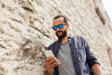 man texting message on smartphone at stone wall