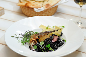 Tasty Italian food.
Fettuccine with the addition of cuttlefish ink sauce and pike caviar on a white plate.
Restaurant supply.