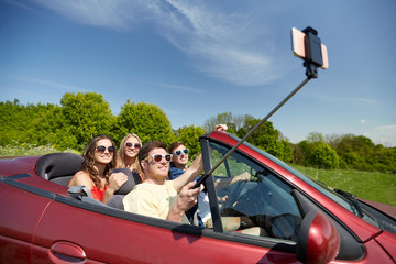 friends driving in cabriolet car and taking selfie