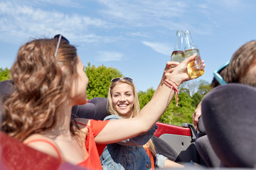 happy friends driving in cabriolet car with beer