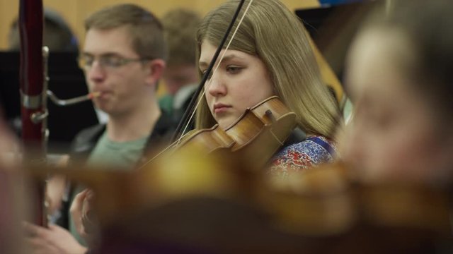 Close up of teenage girl playing violin in orchestra practice / American Fork, Utah, United States
