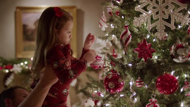 Medium panning shot of father and daughter decorating Christmas tree / Cedar Hills, Utah, United States