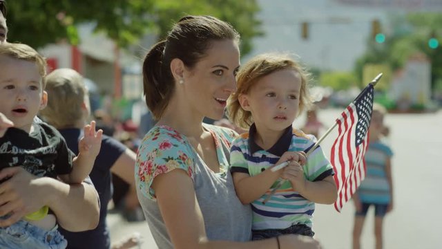 Medium slow motion shot of family watching parade / American Fork, Utah, United States