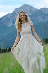Fototapeta na wymiar Junge Frau läuft in einem langen Kleid über eine Bergwiese im Berchtesgadener Land