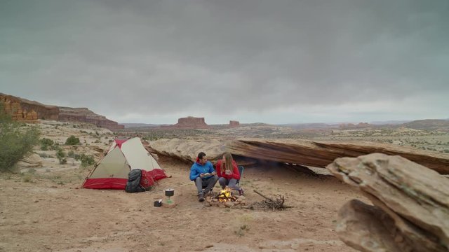 Wide panning shot of couple at campfire in desert / Moab, Utah, United States