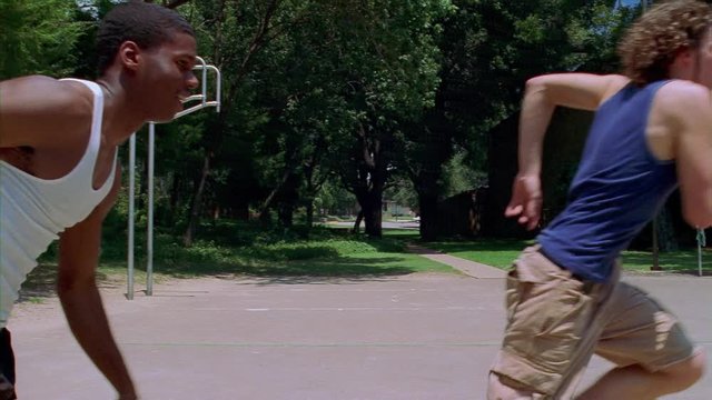 Two teenage boys playing basketball on an outdoor court