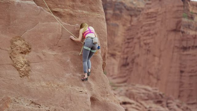 Wide shot of woman climbing on rock formation / Fisher Towers, Utah, United States