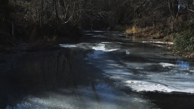 A partially frozen forest stream
