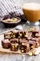 Dark  chocolate cubes with pistachios and cup of coffee on woode