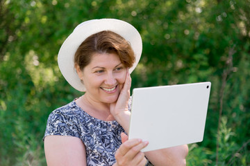 woman in hat with pc tablet outside