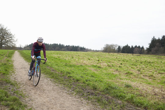Cross-country cyclist riding down a path in open countryside