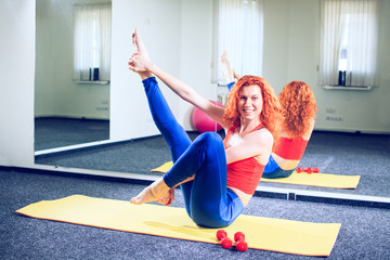 young female instructor doing  pilates exercises in sport club