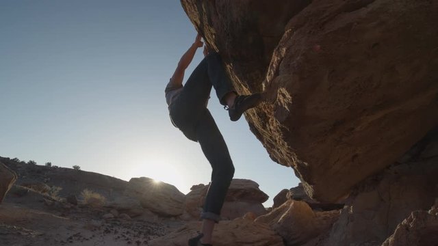 Medium low angle slow motion shot of man climbing rock / Ferron, Utah, United States