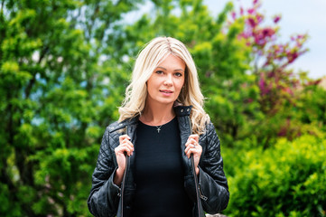 Outdoor portrait of beautiful blond woman wearing black leather jacket