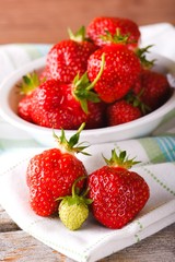Red and green strawberries on towel in front of bowl