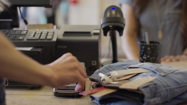 Close up panning shot of cashier swiping credit card for customer in store / American Fork, Utah, United States
