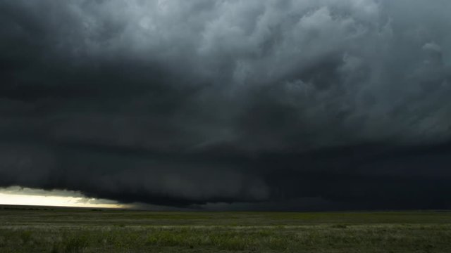 Low fast-moving shelf cloud almost touches windy prairie, time lapse