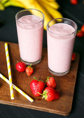 Strawberry and banana smoothie in the glass on black background