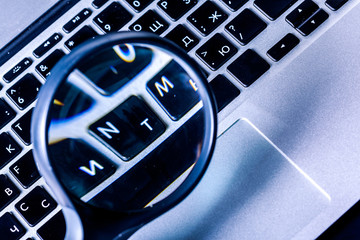 Closeup images of magnifying glass on laptop keyboard