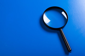 Magnifier on blue background close up