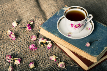 Vintage teapot and cup with blooming tea flowers on wooden background