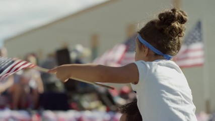Medium slow motion shot of girl waving American flag at parade / American Fork, Utah, United States - Powered by Adobe