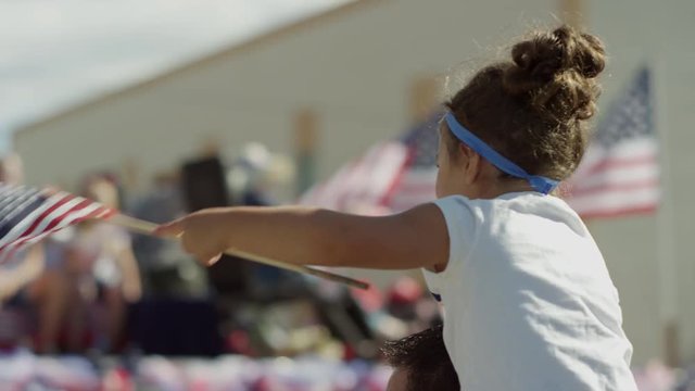 Medium slow motion shot of girl waving American flag at parade / American Fork, Utah, United States