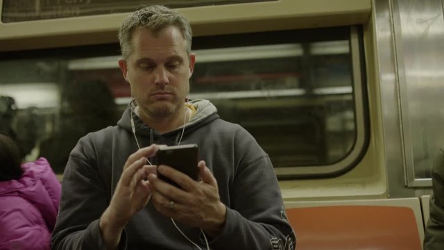 Medium low angle shot of man using cell phone on subway / New York, New York, United States
